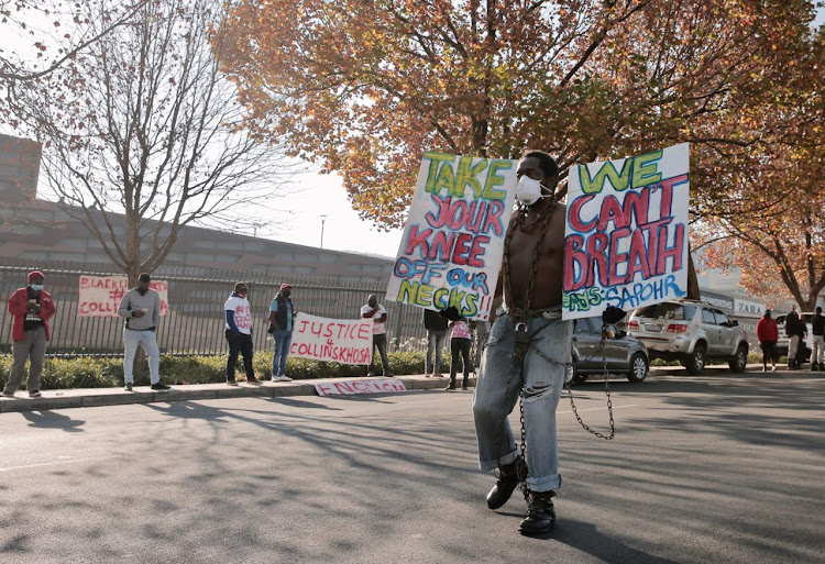 A protester holds up placards as he walks in Sandton on Monday morning.