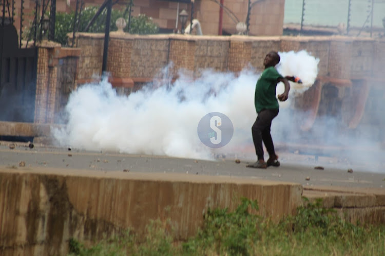 A protester throws back teargas to police during protest in Kisumu on March 20.