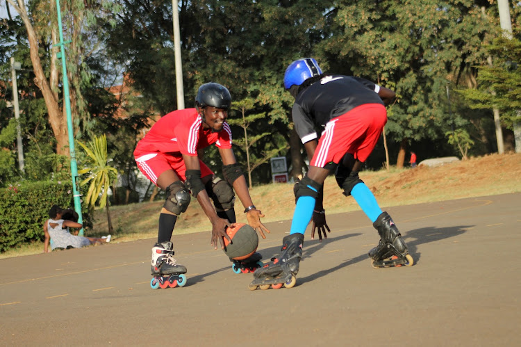 Joseph Alukhala (red) dribbles the ball as George Mbutu (R) plays defensive during their training at the University of Nairobi grounds.