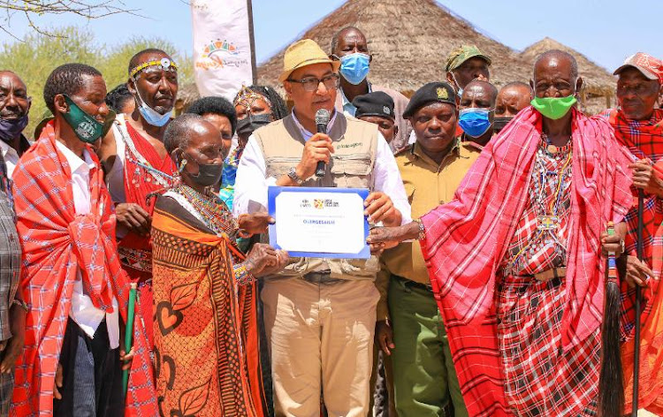 CS for Tourism and Wildlife Najib Balala hands over the UNWTO best tourism village certificate to the Olergasiale community.