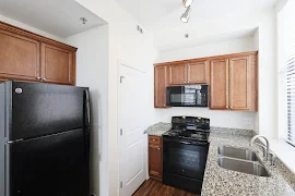 Back corner of kitchen has a pantry closet next to the oven and microwave. Refrigerator is on adjacent wall to the left