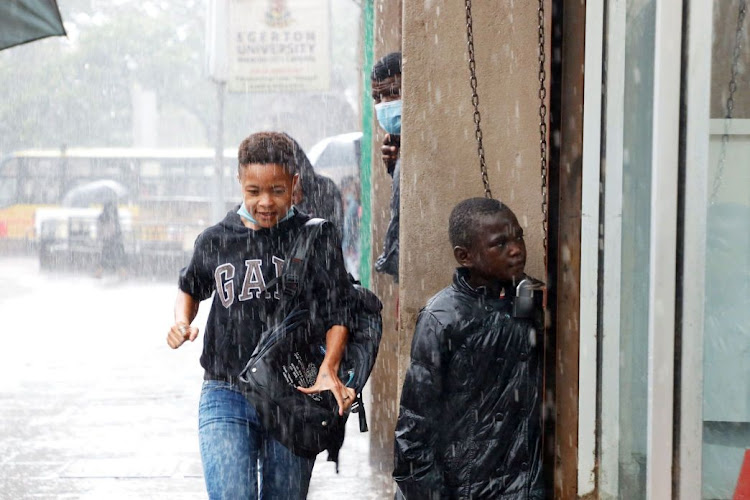 A pedestrian runs as a others seek shelter near Mr Price shop in the CBD on Saturday.