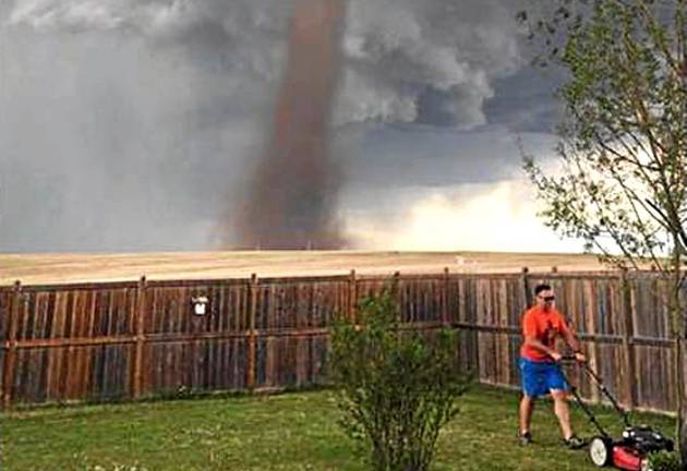 MAGNUM: Theunis Wessels mows his lawn at his home in Alberta, Canada, as a tornado gathers in the background.