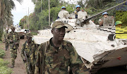 A United Nations peacekeepers' armoured vehicle passes Congolese rebels patrolling a street in Goma in the eastern Democratic Republic of Congo. The assailants, believed to be rebels from the Allied Democratic Forces have targeted at least five villages killing over 60 people.