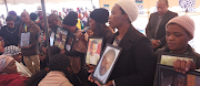 Framed pictures of the deceased were held up by residents at the memorial service held in Nomzamo in Orlando East on Thursday. 