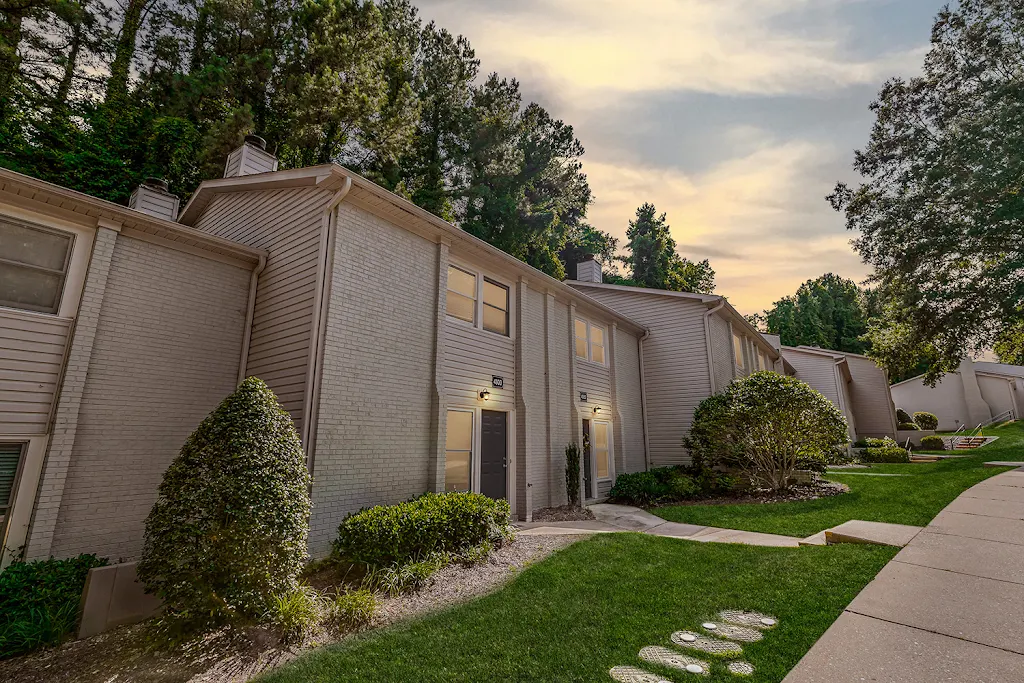 Apartments of Westgrove building with white siding and brick and dark gray doors at dusk