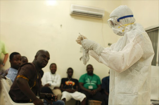 Medical personnel demonstrates personal protective equipment to educate team members on the Ebola virus in Liberia.