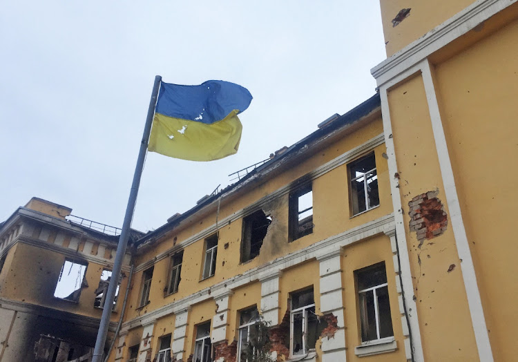 The Ukrainian national flag is seen in front of a school which, according to local residents, was on fire after shelling, as Russia's invasion of Ukraine continues, in Kharkiv, Ukraine February 28 2022. Picture: REUTERS/VITALIY GNIDYI