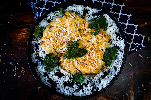 A platter of Grilled Coconut Chicken with toasted coconut on top.