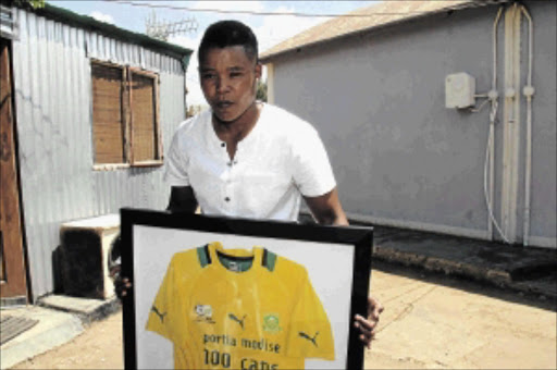 achiever: Portia Modise holds a framed jersey in honour of her 100 caps with Banyana Banyana at her family home in Soweto. Her caps tally is now 119, with 100 goals PHOTO: Bafana Mahlangu