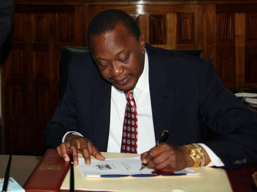 National Assembly Majority leader Aden Duale and Speaker Justin Muturi look on as President Uhuru Kenyatta signs bills into law at State House, Nairobi, in this file photo. Photo/PSCU