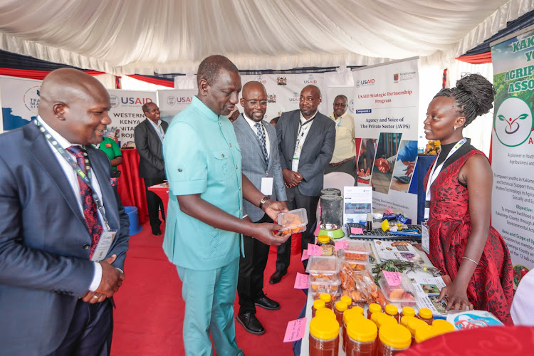 President William Ruto interacting with a honey seller at Masinde Muliro University during the Kakamega County International Investment Conference on March 20, 2024