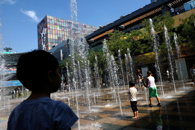 Children cool off in a water fountain amid an orange alert for heatwave, at a shopping area in Beijing, China, on June 22 2023. Picture: REUTERS/TINGSHU WANG