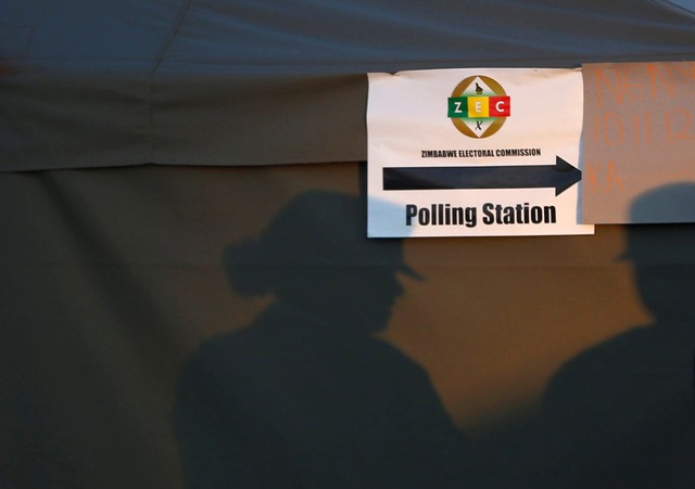 Police officers cast shadows on a tent of a polling station during the general elections in Harare, Zimbabwe, July 30, 2018.