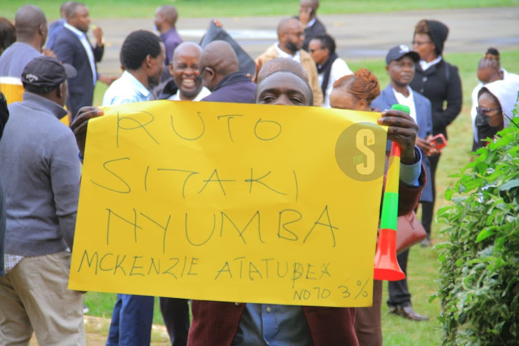 A public servant with a written message to President William Ruto while demonstrating against the 3% housing levy in Nairobi university on May 29, 2023