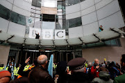 A protester waves a flag next to the BBC logo at the company's headquarters during an Extinction Rebellion demonstration in London, Britain October 11, 2019. 
