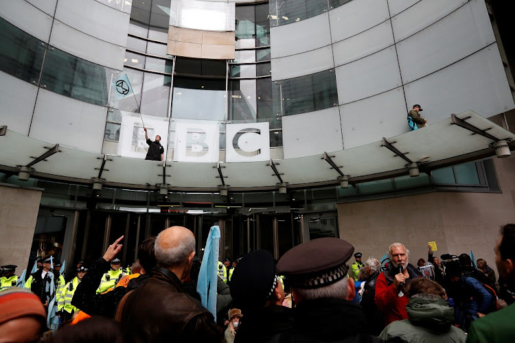 A protester waves a flag next to the BBC logo at the company's headquarters during an Extinction Rebellion demonstration in London, Britain October 11, 2019.