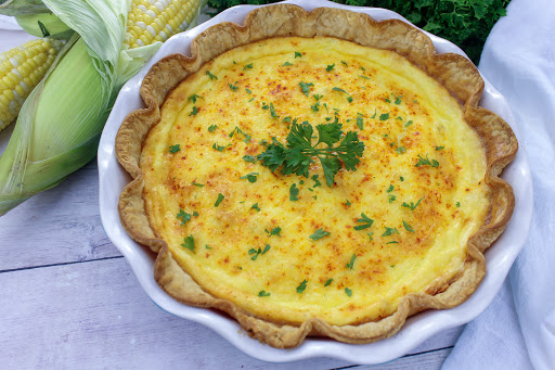 Fresh corn pie in a white pie plate.