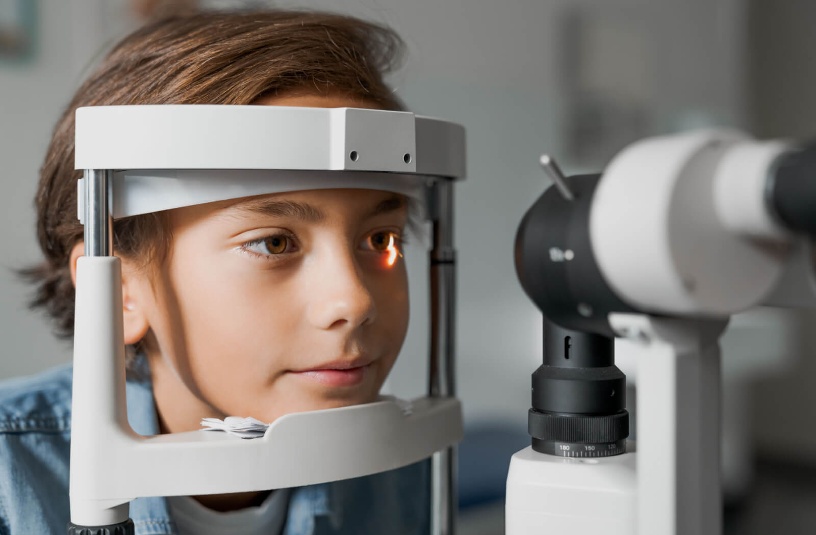 A child has his eyes checked with a slit lamp