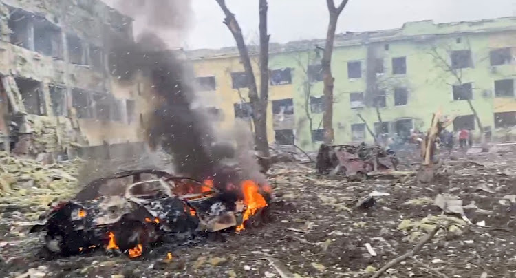 A car burns after the destruction of Mariupol children's hospital as Russia's invasion of Ukraine continues, in Mariupol, Ukraine, March 9, 2022 in this still image from a handout video obtained by Reuters.