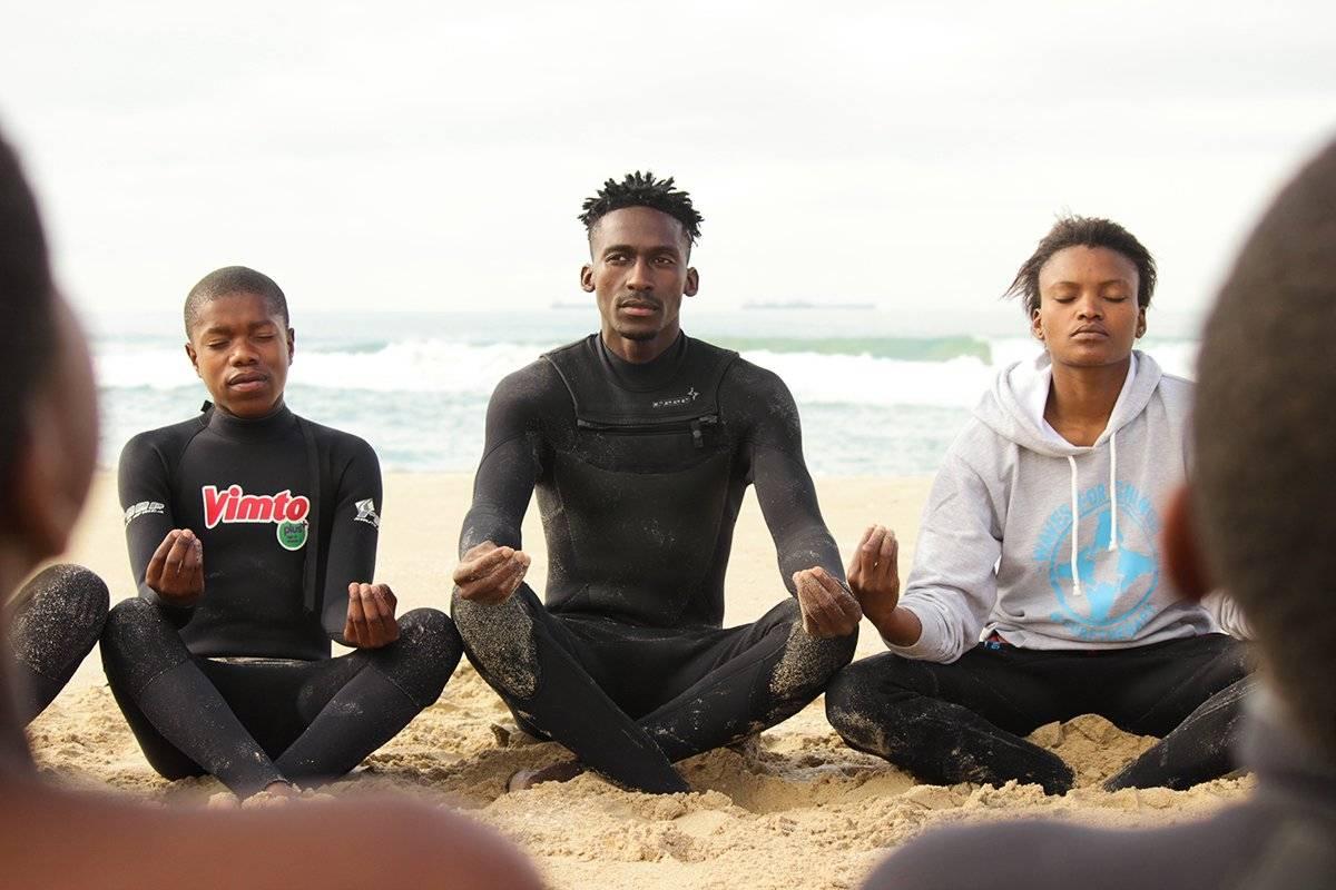 A group of children sitting on the beach  Description automatically generated with low confidence