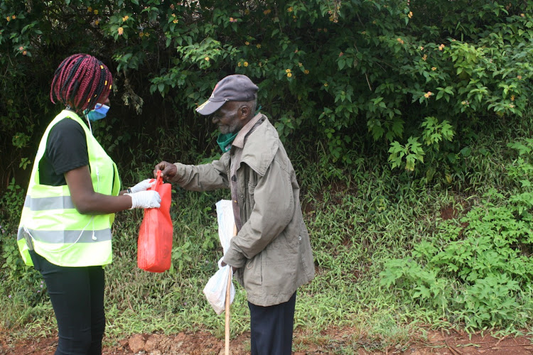 A volunteer presents food to an elderly man in Kiharu