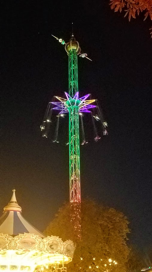 The Star Flyer is the high swing carousel ride in the back right, and the the Swing Carousel to the left from 1907 used at Halloween and Christmas / Visiting Tivoli Amusement park during Halloween decoration time, October 2018