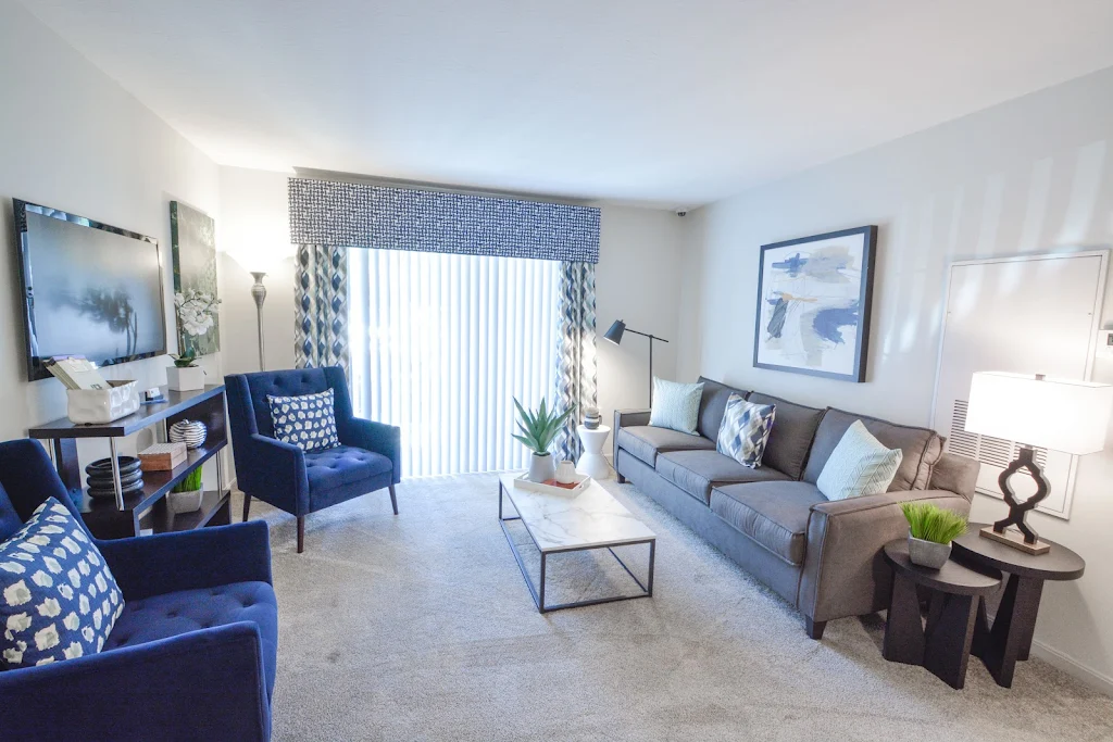 Model living room with light walls, neutral carpet and blue accent decor