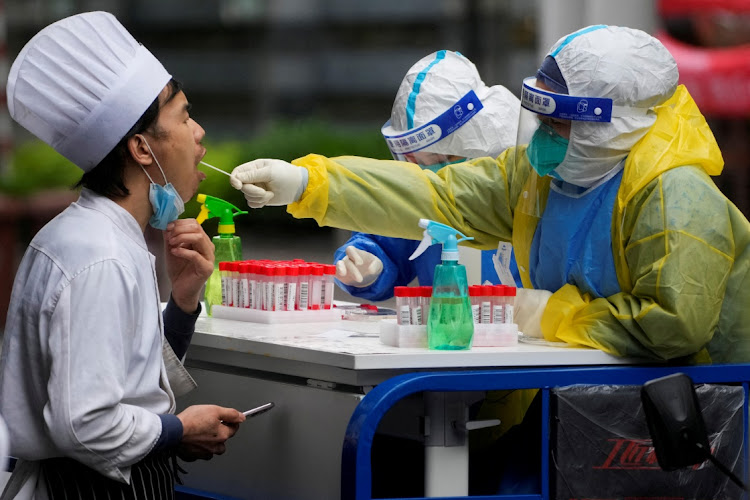 A medical worker in a protective suit collects a swab sample from a chef for nucleic acid testing, during lockdown, amid the coronavirus disease (Covid-19) pandemic, in Shanghai, China, May 13, 2022.