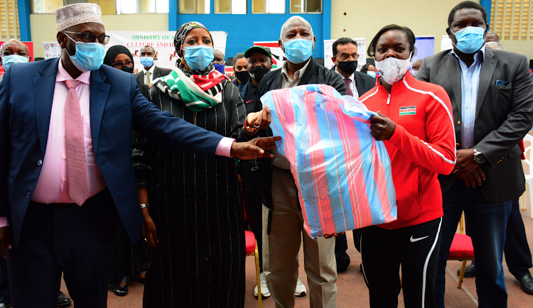 Sports CS Amina Mohammed presents food donation to athlete Mary Moraa at Nyayo Stadium as CAS Noor Hassan (L), AK president Jack Tuwei (C) and NOCK vice president Shadrack Maluki (R) looks on.