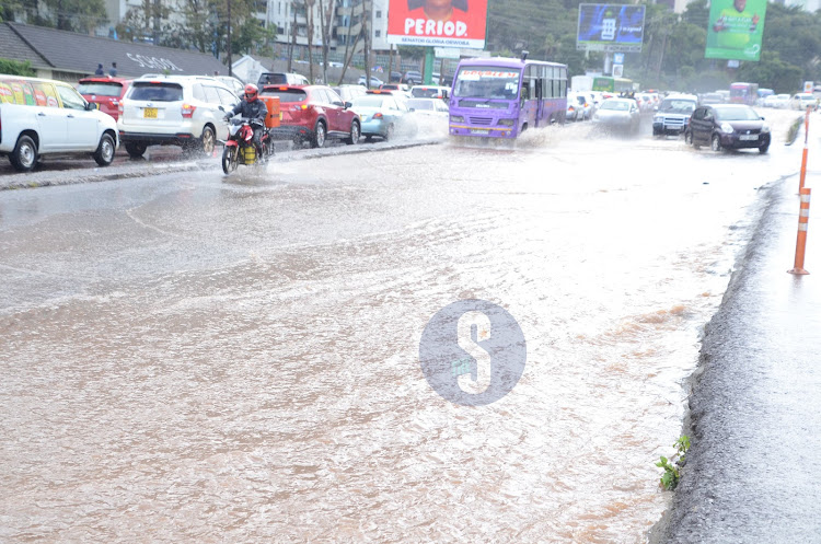 Motorists drive through flooded road after heavy downpour on April 24, 2024.