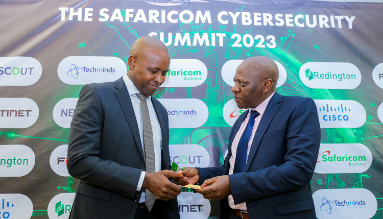 Principal Secretary State Department of Co-operatives Patrick Kilemi consults with Chief Corporate Security Officer Nicholas Mulila at Safaricom PLC during the Cyber Security Summit held at Movenpick Hotel on October 23, 2023.