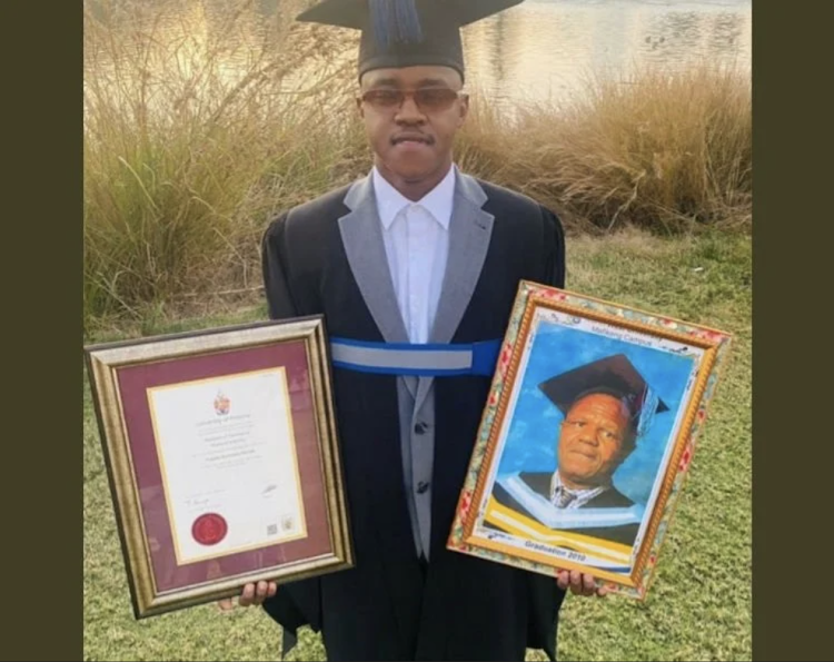 Thapelo Menwe holding up his degree after his graduation.