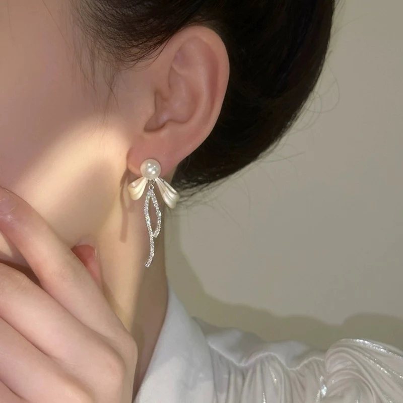 Boucles d'oreilles à pompon bleu marine avec nœud long pour femme. Un accessoire élégant et féminin pour compléter toutes vos tenues.