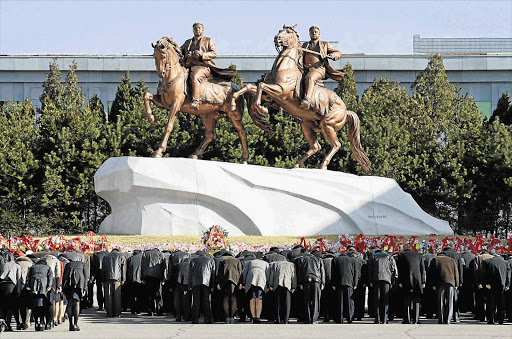 North Koreans bow to bronze statues of their country's founder, Kim Il-sung, left, and late leader Kim Jong-il in Pyongyang yesterday, a day before the birthday of Kim Il-sung