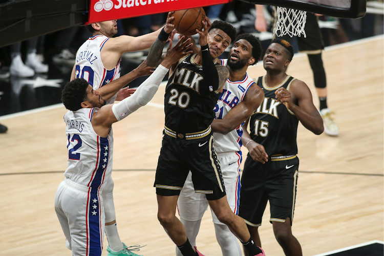 Atlanta Hawks forward John Collins (20) grabs a rebound under challenge from Philadelphia 76ers forward Tobias Harris (12) and centre Joel Embiid (21).