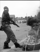 BURNING ISSUE: A policeman removes a tyre set alight by minworkers who protested after they were told that they were going to be laid off.  25/11/2008.  Pic. Unknown.