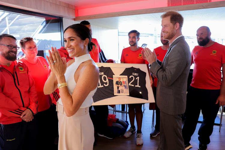 Meghan Markle and Prince Harry are presented with sports shirts bearing their children's names by Invictus athletes.