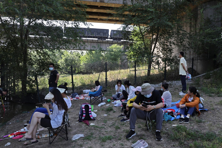 People have picnics under a railway bridge as a train moves past, amid the coronavirus disease (COVID-19) outbreak, in Beijing, China May 21, 2022.