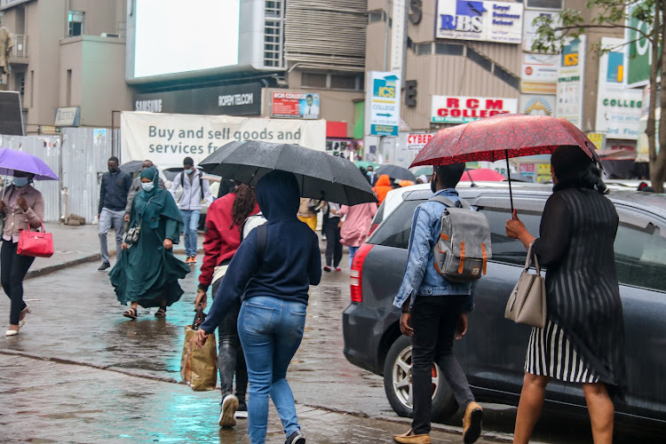 A number of city dwellers use umbrellas to take cover from the rainfall