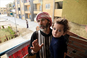 Syrian Mohamed Amin, 43, who fled his country with his family due to the war, stands with his child next to a baking-oven at a make-shift bakery set up on the balcony of his apartment in the Egyptian capital Cairo, on March 8, 2017. After fleeing to Egypt from the war devastating their country, more Syrians are abandoning migration to the West fearing racism and culture shock, and instead are settling down in Cairo.