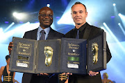 Roger Milla (L) and Andres Iniesta receive the Golden Foot Award trophy during the Golden Foot Award 2014 ceremony at Sporting Club on October 13, 2014 in Monte-Carlo, Monaco. 