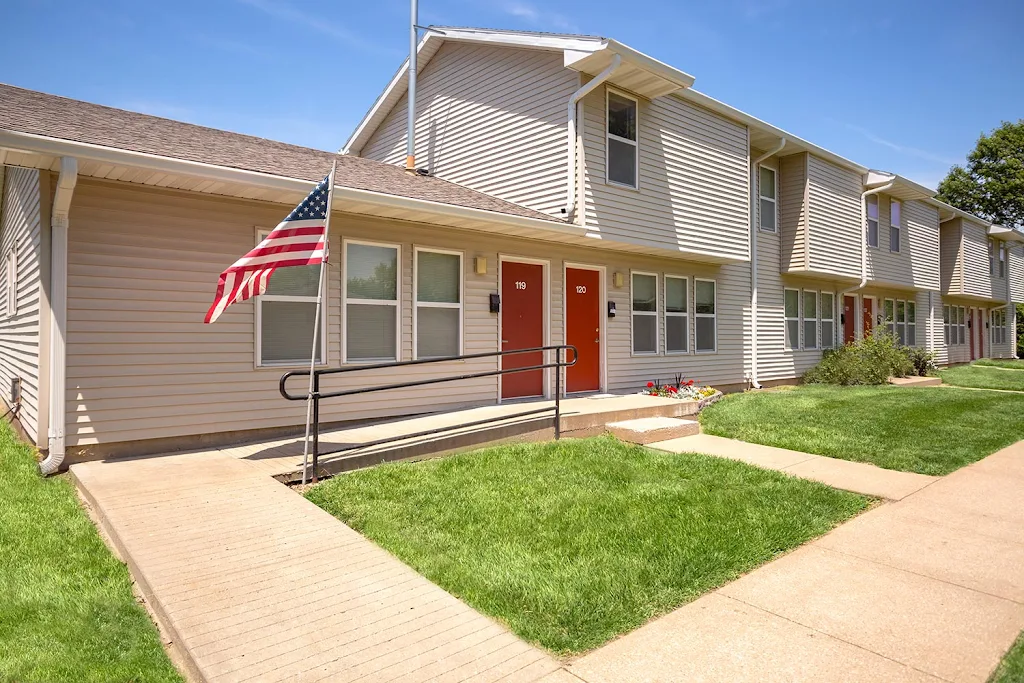 Cedar Tree building featuring flag, ramp, stairs, red doors