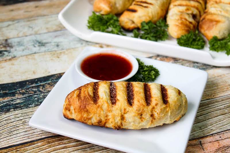 A Grilled Chipotle Chicken Pizza Roll On A Plate With Dipping Sauce.