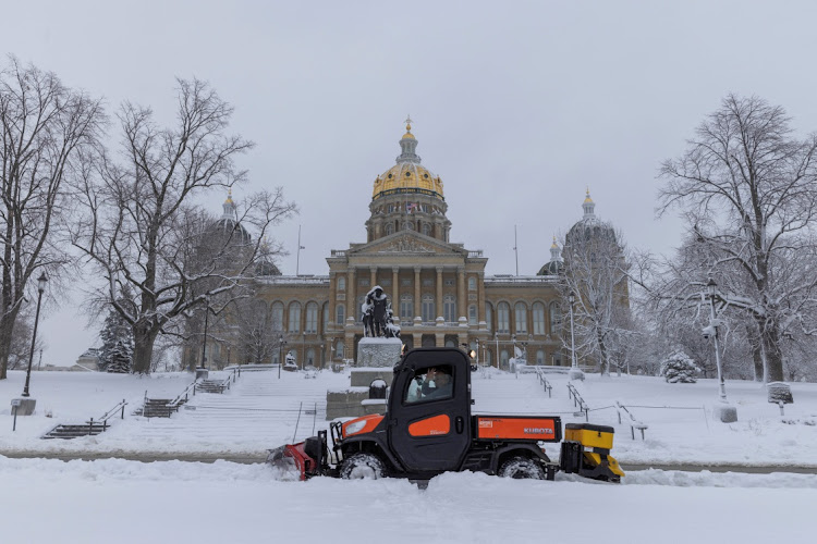 Workers remove snow from the sidewalk outside of the Iowa State Capitol Building after a snowstorm left several inches of snow in Des Moines, Iowa, U.S., January 9, 2024.