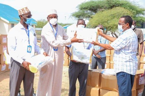 FCDC representative Abdirahman Maalim hands over some of the PPEs to Garissa county chief officer for Health and Sanitation Abdi Shukri on Saturday. The PPEs were donated by the Swiss government.