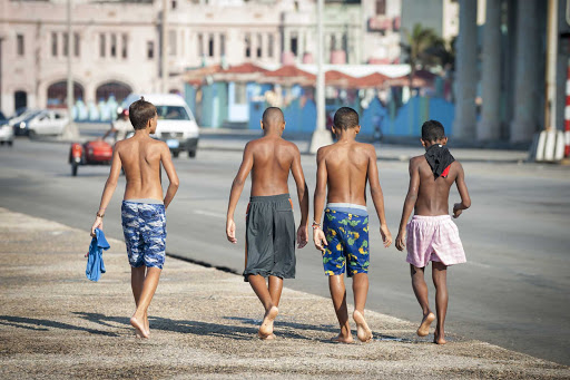 Boys walking down a sidewalk in Cuba.