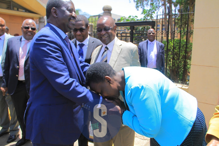 A woman kisses ODM leader Raila Odinga's hand outside Parliament