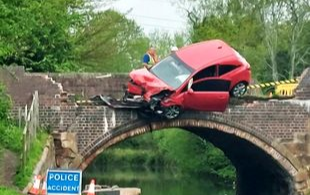 A car left hanging over a bridge after an accident in the United Kingdom on May 6, 2023.