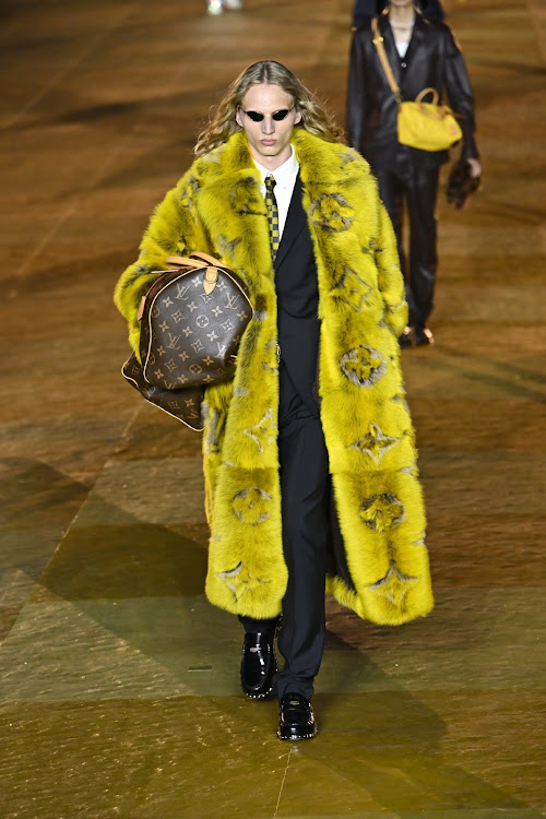 Model walks the runway in acid yellow fur coat during the Louis Vuitton Menswear Spring/Summer 2024 show in Paris.